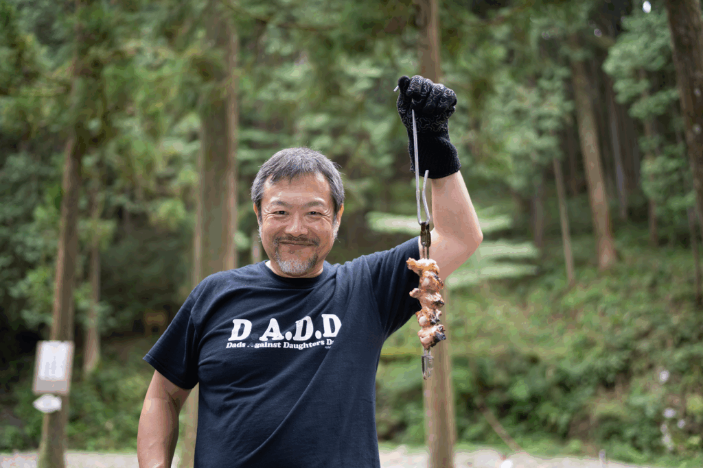 串焼きにした鶏手羽中を手に微笑む中川