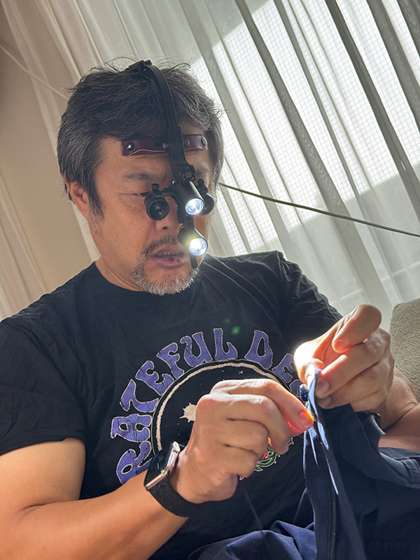 手術用拡大鏡で裁縫する中川